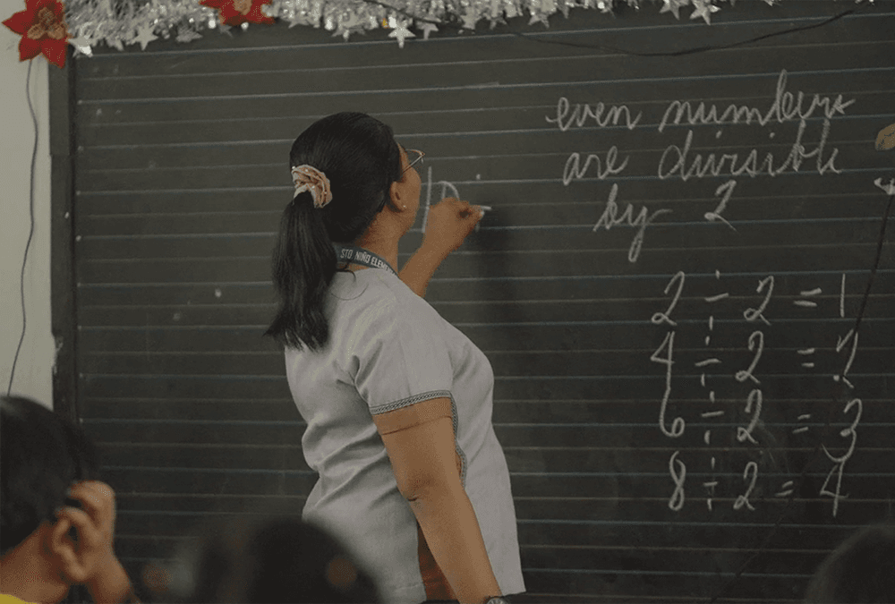 Teacher writing on a chalkboard in a classroom in the Philippines